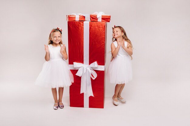 Duas meninas com presentes de Natal em um fundo branco e um grande presente