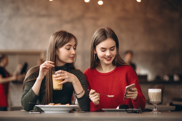 Duas meninas com telefone sentado em um café