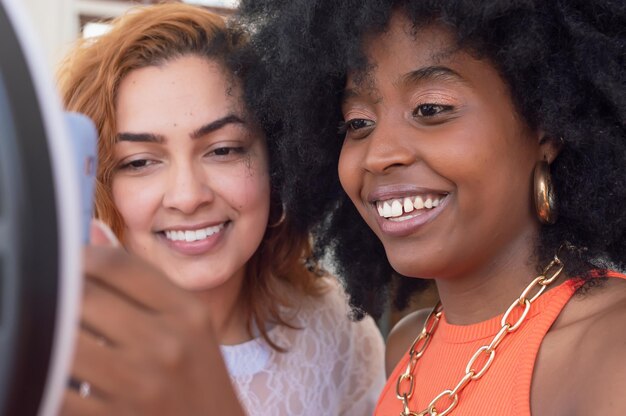 Duas meninas de diferentes etnias sorrindo e verificando um telefone