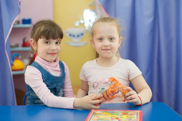 Duas meninas de seis anos com um brinquedo Namoradas no jardim de infância