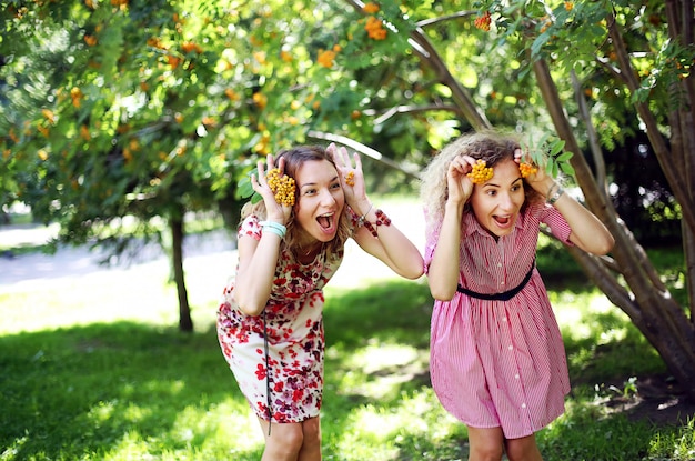 Foto duas meninas de sorriso bonitas abraçaram no parque do verão.