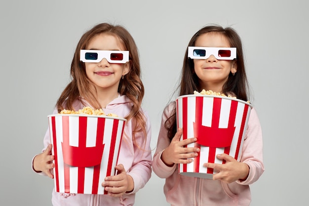 Duas meninas em óculos 3d redblue segurando baldes de pipoca