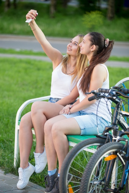 Foto duas meninas em um banco com bicicletas