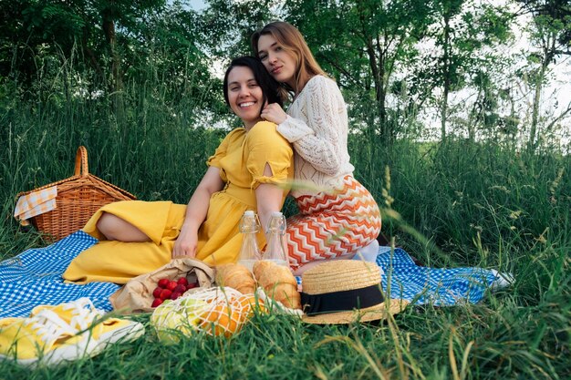 Duas meninas em uma data sentam-se em um cobertor azul para um piquenique na natureza