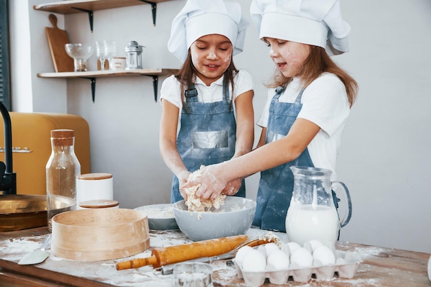 Duas meninas em uniforme de chef azul preparando comida na cozinha