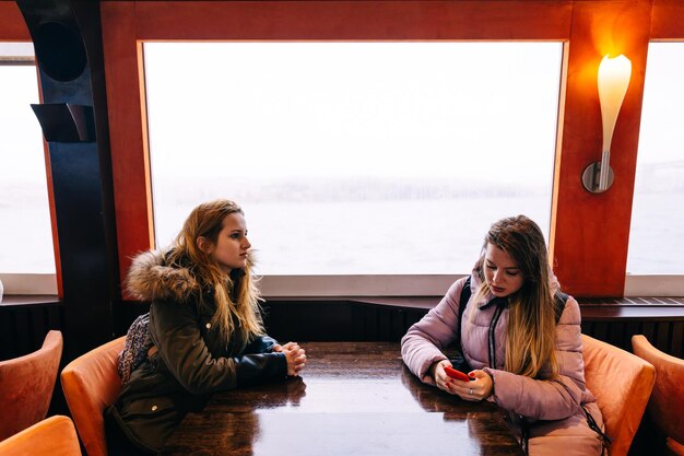 Foto duas meninas estão pensativas sentadas em uma mesa viajando de barco