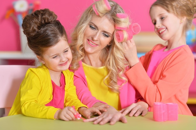 Duas meninas fazendo manicure e penteado para sua mãe