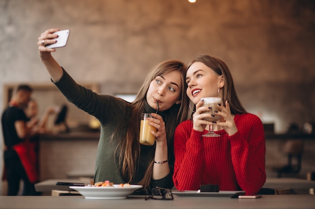 Foto duas meninas fazendo selfie em um café