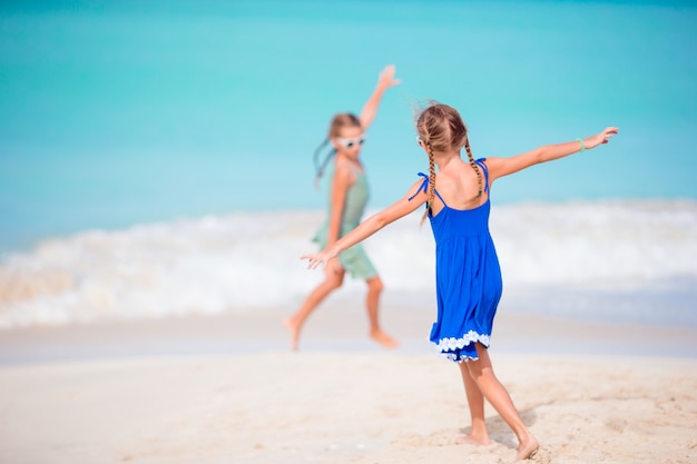 Duas meninas felizes se divertem muito na praia tropical jogando juntos
