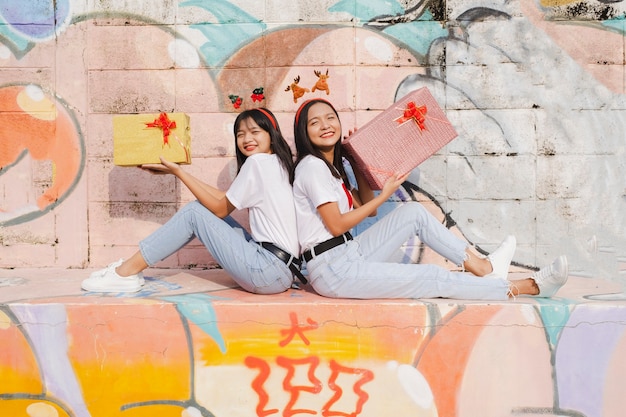 Duas meninas felizes usam chapéu de natal em fundo colorido.