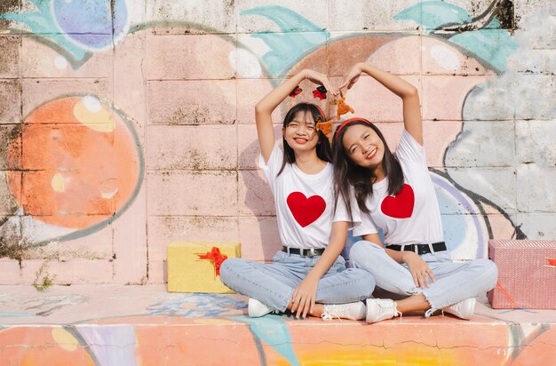 Duas meninas felizes usam chapéu de natal em fundo colorido.