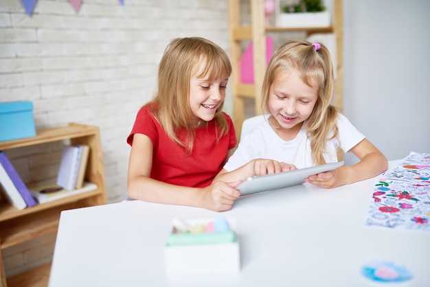 Duas meninas felizes usando tablet digital