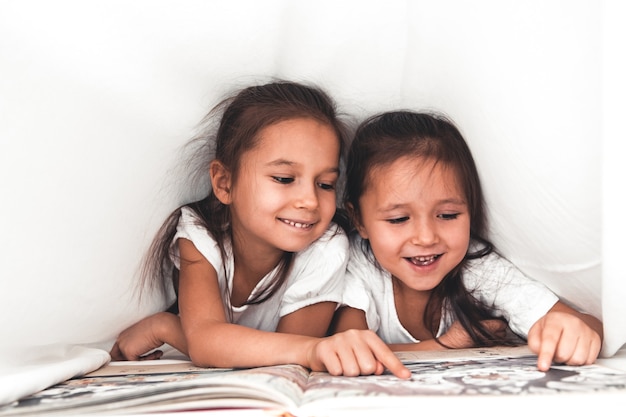 Duas meninas lendo embaixo do cobertor