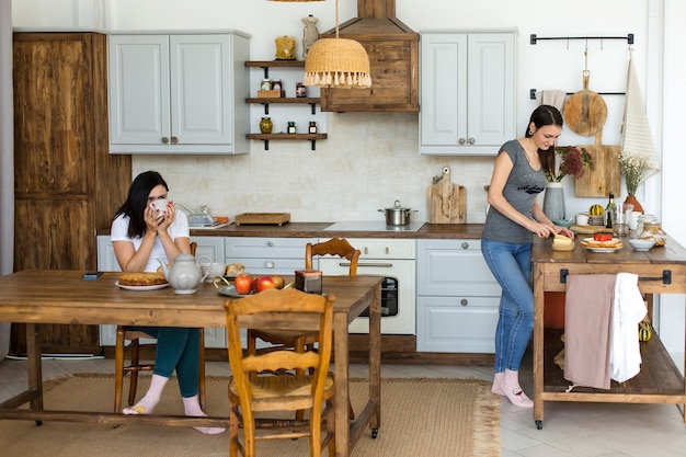 Duas meninas morenas estão bebendo chá com bolo e doces na mesa. Foto de alta qualidade