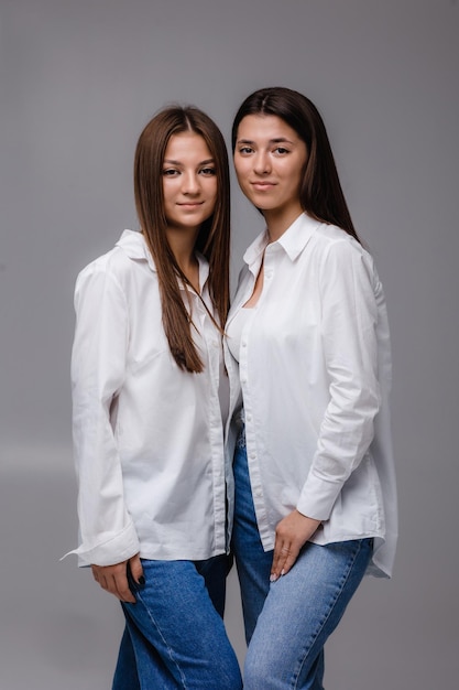 duas meninas posando para uma foto com uma vestindo uma camisa branca