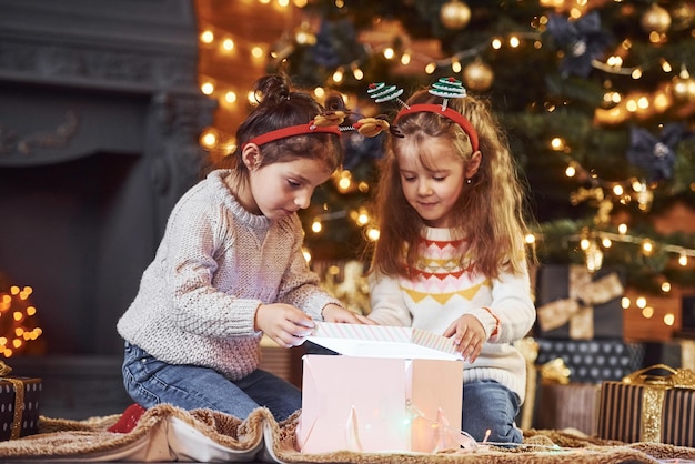 Duas meninas se divertem no quarto decorado de natal com caixas de presente.