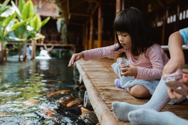 Duas meninas se divertindo alimentando peixes koi