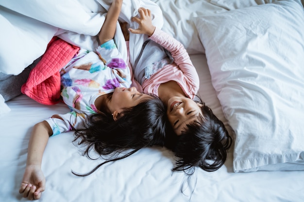 Duas meninas se divertindo e rindo na cama