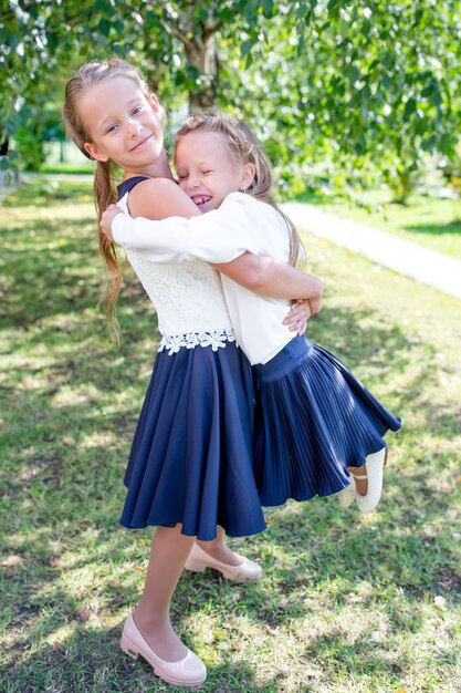 Duas meninas smilling bonitos que levantam na frente de sua escola.