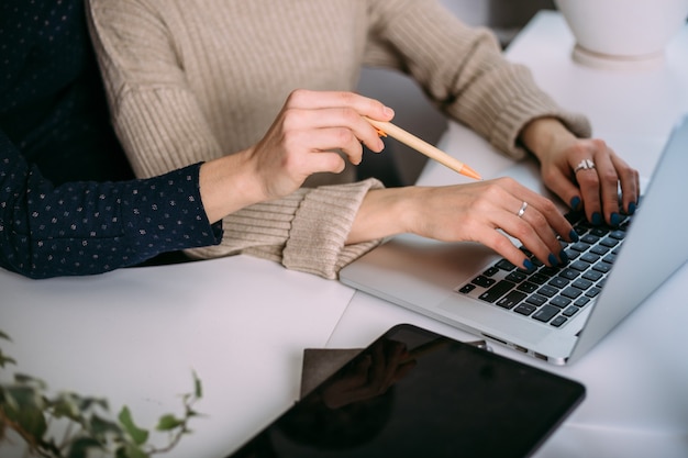 Duas meninas trabalham lado a lado no escritório em um laptop. Interação dos colegas de trabalho. A psicologia das relações de trabalho.