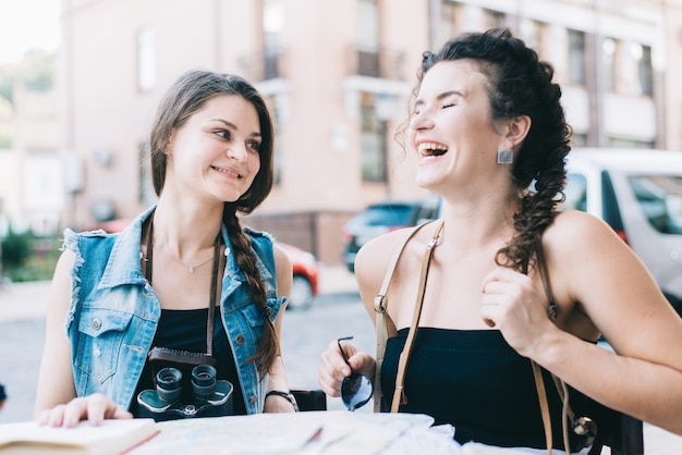 Duas meninas turísticas bonitas com um mapa andam pela cidade velha