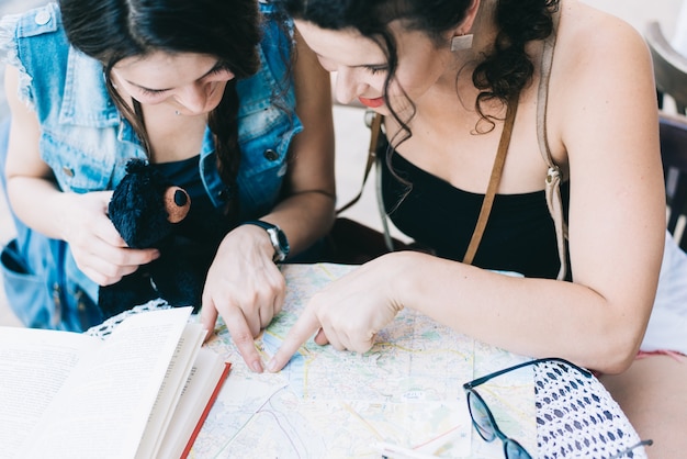 Duas meninas turísticas bonitas com um mapa andam pela cidade velha