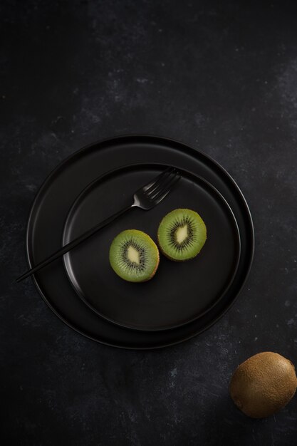 Duas metades de kiwi verde na placa preta. fruta madura fresca. conceito de comida saudável.