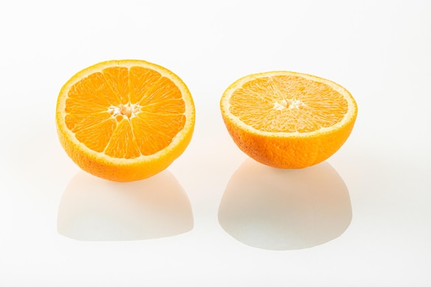 Duas metades de uma laranja com reflexo em um fundo de espelho branco