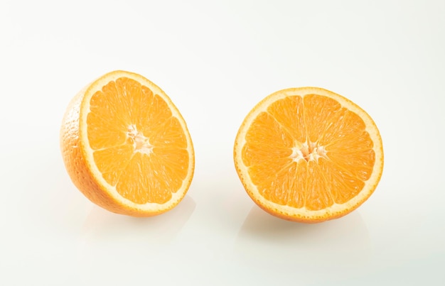 Duas metades de uma laranja com reflexo em um fundo de espelho branco
