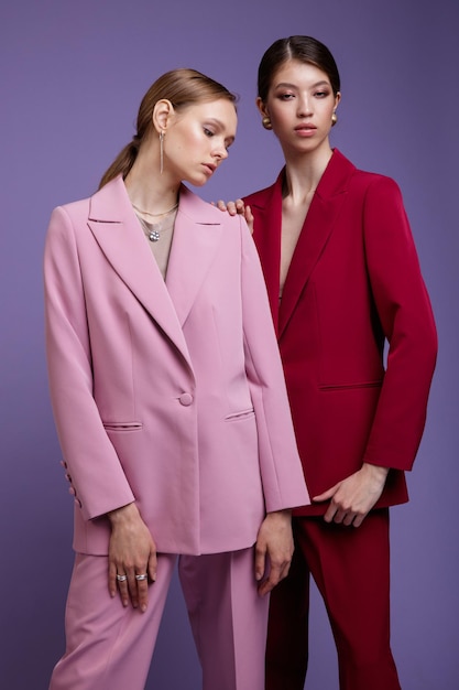 Duas modelos asiáticas e europeias da moda em ternos superdimensionados rosa claro e vermelho