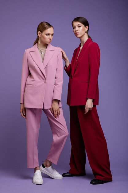 Duas modelos asiáticas e europeias da moda em ternos superdimensionados rosa claro e vermelho