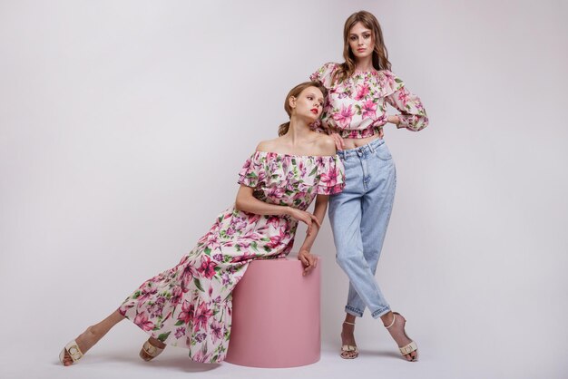 Duas modelos de alta costura em vestido longo com blusa vermelha com padrão floral jeans.