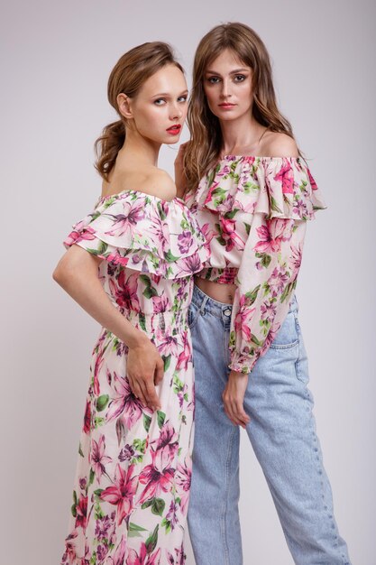 Duas modelos de alta costura em vestido longo com blusa vermelha com padrão floral jeans.