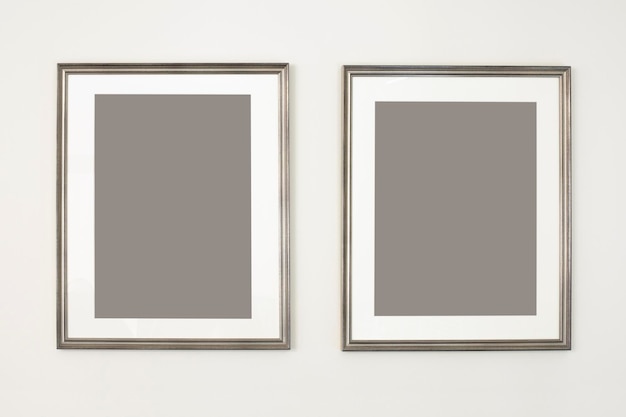 Duas molduras verticais, simulação de pôster. Porta-retratos de prata vazios pendurados na parede. Espaço livre para sua foto ou texto, copie o espaço. Design minimalista.