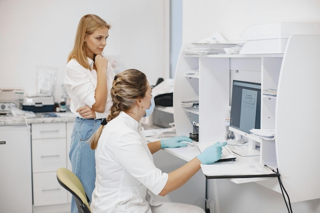 duas mulheres a trabalhar num computador com um monitor atrás delas