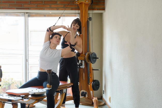 duas mulheres adultas a treinarem juntas com uma máquina girotónica em casa