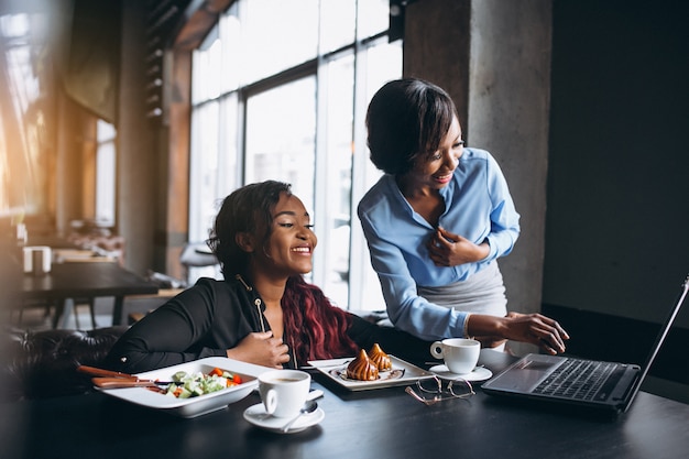 Duas mulheres afro-americanas com laptop e almoço