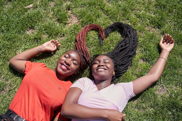 Duas mulheres afroamericanas deitadas fazendo formato de coração com suas tranças