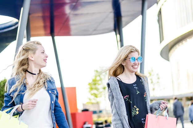 Duas mulheres amigas a fazer compras com sacos no centro comercial ao ar livre