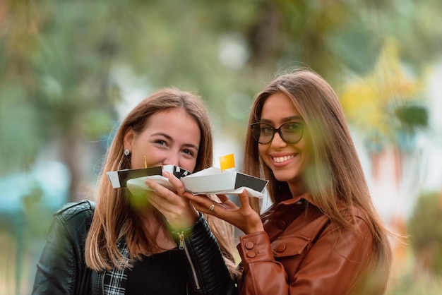 Duas mulheres andando pela cidade moderna e comendo poffertjes frescos Foco seletivo