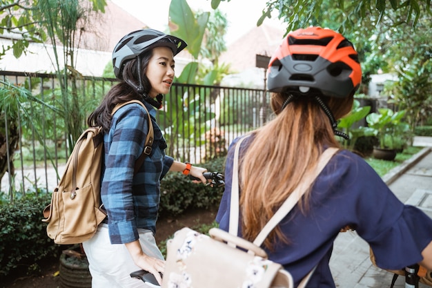 Duas mulheres asiáticas conversando e andando enquanto caminha com bicicletas dobráveis