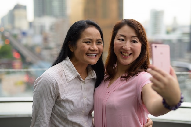 Duas mulheres asiáticas maduras juntas contra a vista da cidade