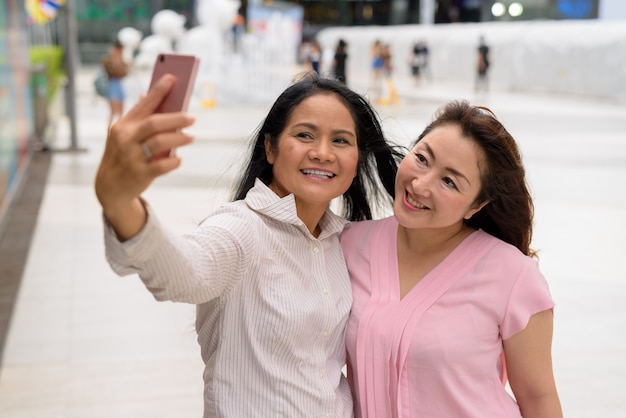 Duas mulheres asiáticas maduras juntas fora do shopping na cidade de Bangkok