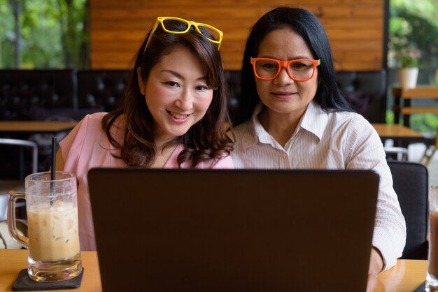 Duas mulheres asiáticas maduras juntas saindo na cafeteria