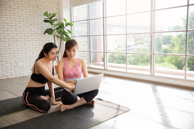 Duas mulheres asiáticas treinam fitness usando um tutorial online