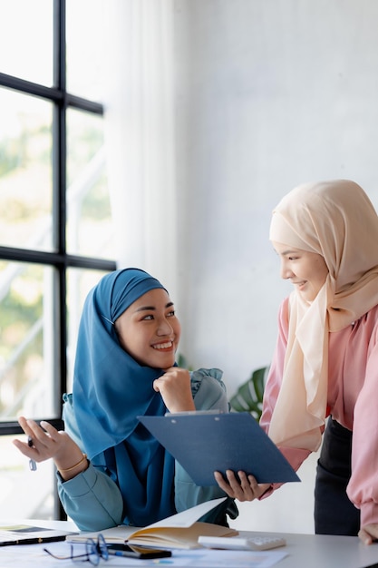 Duas mulheres asiáticas vestidas de hijab estão fazendo brainstorming juntas em uma sala de conferências para uma startup administrada por uma jovem talentosa O conceito de gerenciamento administra a empresa de líderes femininas para expandir a empresa