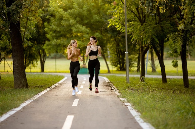 Duas mulheres bonitas correndo na pista do parque