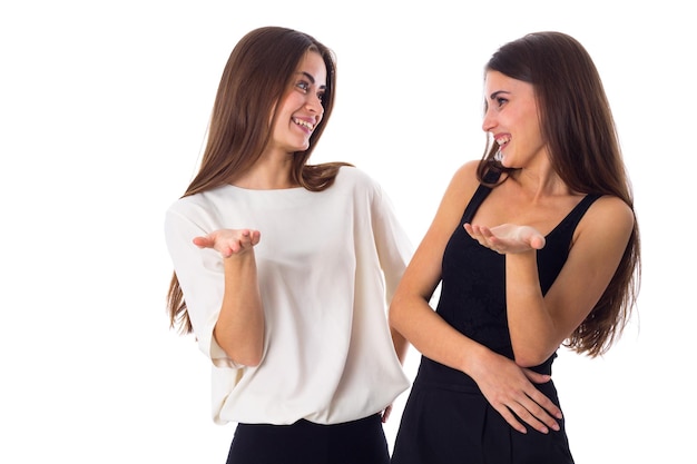 Foto duas mulheres bonitas em camisas pretas e brancas falando sobre fundo branco no estúdio