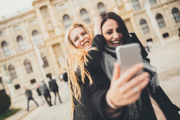 Duas mulheres bonitas fazendo selfie na cidade