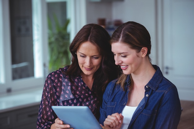 Duas mulheres bonitas usando tablet digital na cozinha